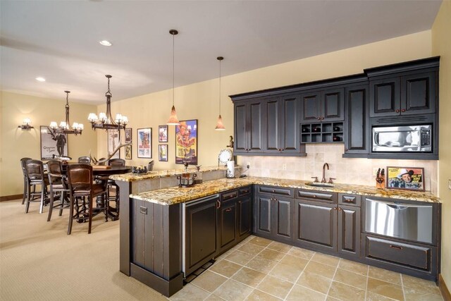 kitchen featuring stainless steel microwave, kitchen peninsula, hanging light fixtures, and an inviting chandelier