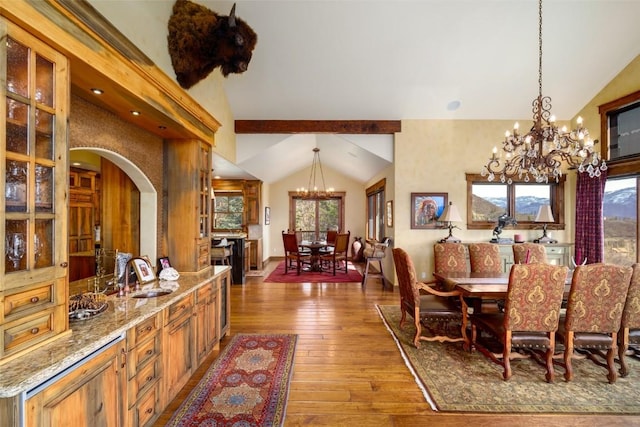 dining area featuring hardwood / wood-style floors, sink, lofted ceiling with beams, and a notable chandelier