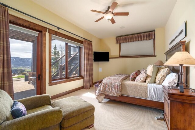 bedroom featuring access to exterior, a mountain view, ceiling fan, and light carpet