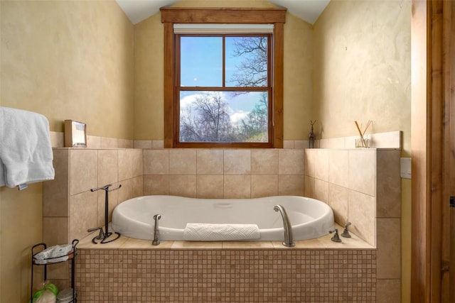 bathroom featuring tiled bath and vaulted ceiling