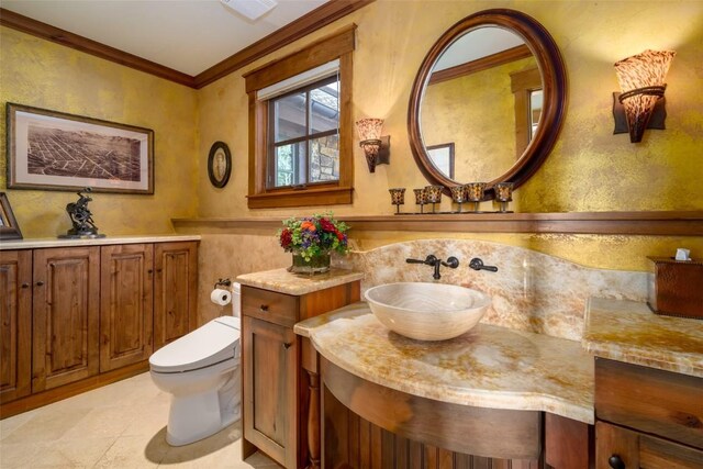 bathroom with vanity, toilet, and ornamental molding