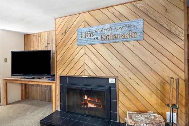 details with carpet, a tile fireplace, and wood walls