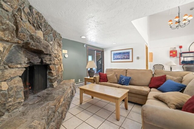 living room with light tile patterned flooring, a stone fireplace, a textured ceiling, baseboard heating, and a chandelier