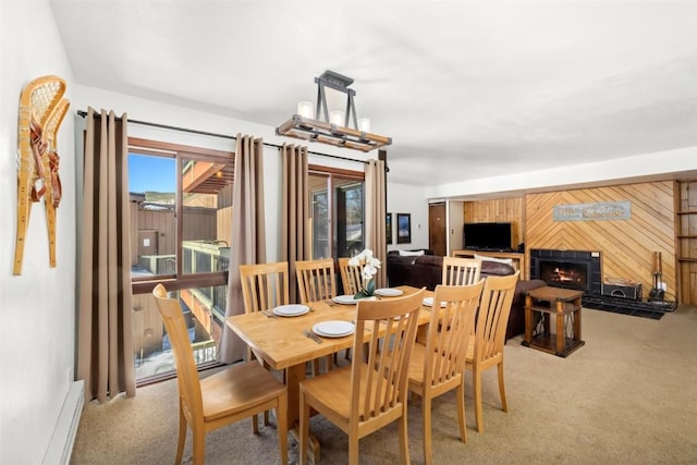 carpeted dining space with a fireplace and wooden walls