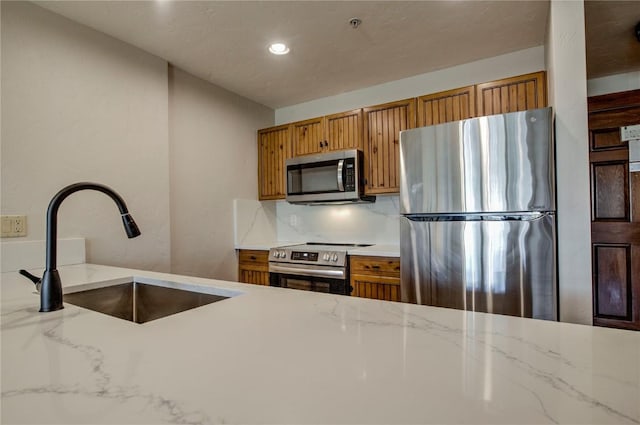 kitchen featuring sink, backsplash, stainless steel appliances, and light stone countertops