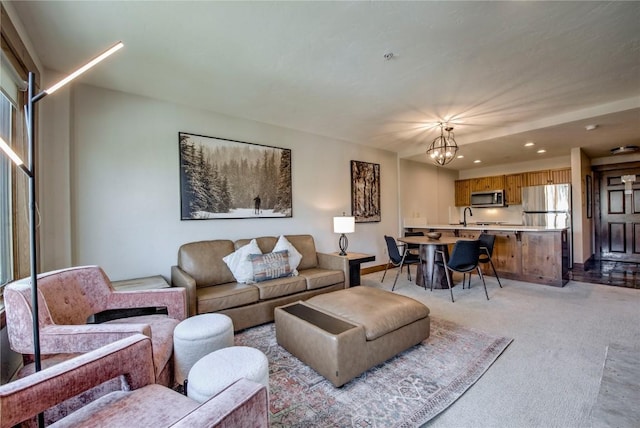 carpeted living room featuring an inviting chandelier and sink