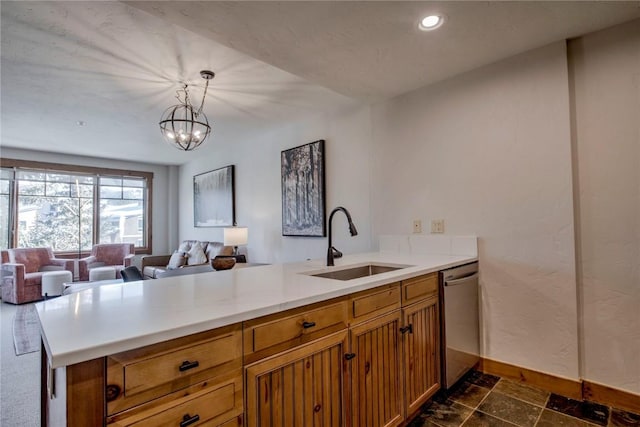 kitchen featuring pendant lighting, stainless steel dishwasher, kitchen peninsula, and sink