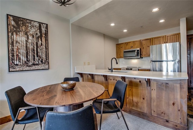 kitchen featuring light carpet, sink, kitchen peninsula, and appliances with stainless steel finishes