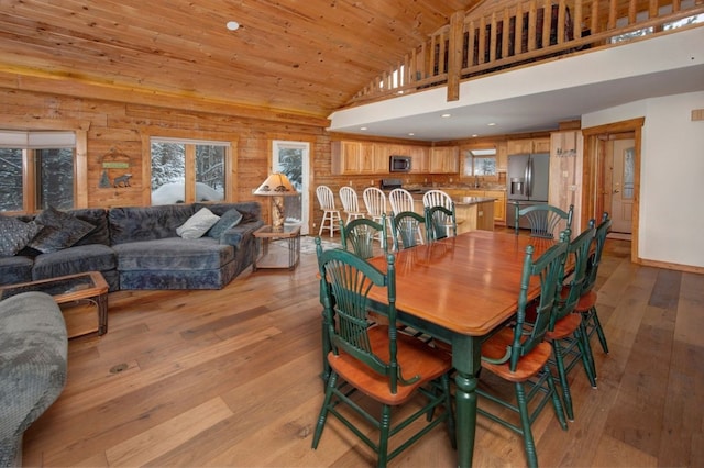 dining area featuring wooden walls, high vaulted ceiling, light hardwood / wood-style floors, and wooden ceiling