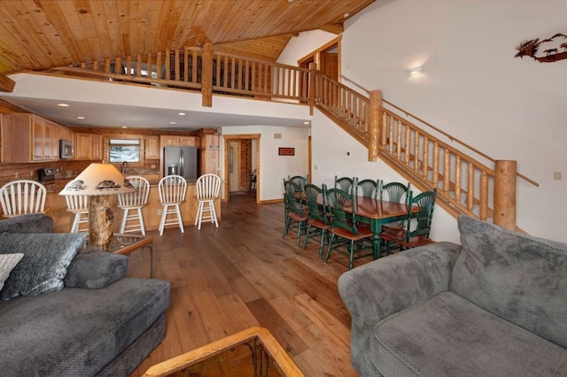 living room with high vaulted ceiling, wood walls, sink, wood ceiling, and light wood-type flooring