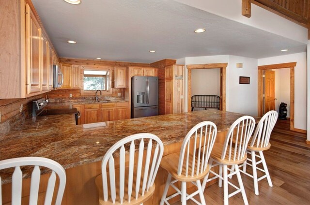 kitchen with dark wood-type flooring, appliances with stainless steel finishes, kitchen peninsula, and sink