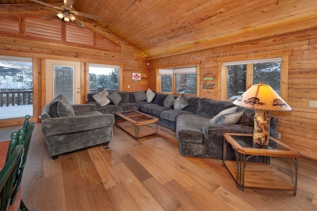 living room featuring wood walls, high vaulted ceiling, light wood-type flooring, wooden ceiling, and ceiling fan