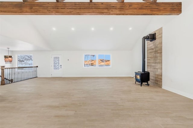 unfurnished living room with lofted ceiling with beams, a healthy amount of sunlight, light wood-type flooring, and a wood stove