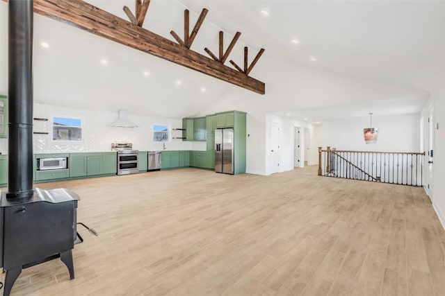 living room featuring vaulted ceiling with beams, light hardwood / wood-style flooring, a wood stove, and sink