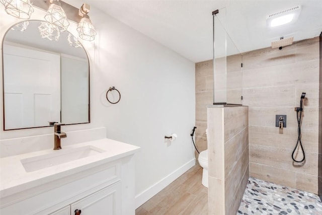 bathroom featuring tiled shower, hardwood / wood-style floors, vanity, and toilet