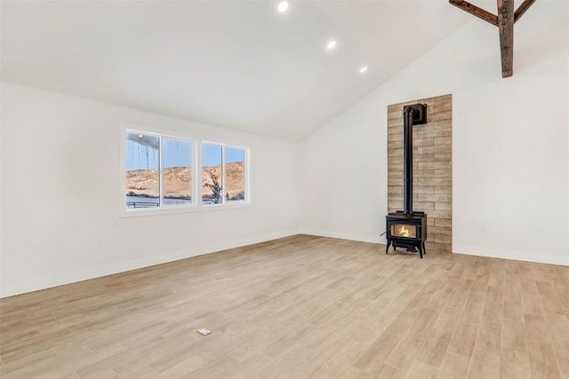 unfurnished living room featuring a wood stove, light hardwood / wood-style floors, and vaulted ceiling with beams