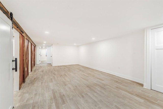 basement featuring a barn door and light hardwood / wood-style floors