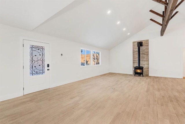 unfurnished living room with a wood stove, high vaulted ceiling, and light wood-type flooring