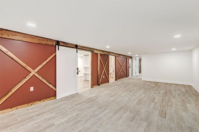 basement with a barn door and light wood-type flooring