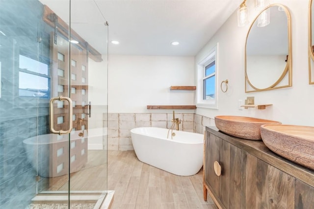 bathroom featuring vanity, independent shower and bath, and tile walls