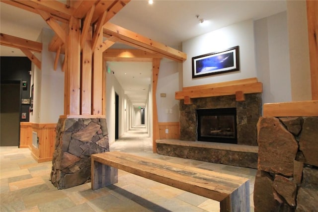 living room featuring stone finish flooring, a wainscoted wall, and a fireplace