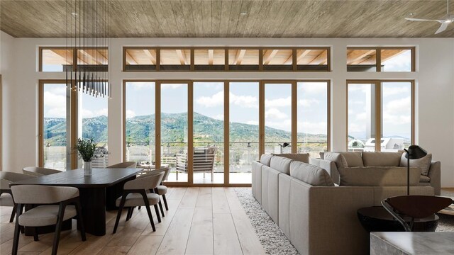 living room with a mountain view, plenty of natural light, wooden ceiling, and light wood-type flooring