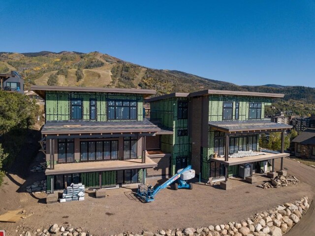 back of property with a mountain view and a balcony