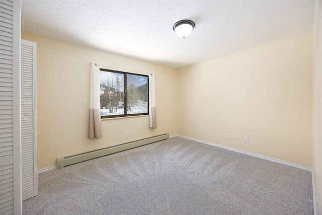 unfurnished bedroom featuring baseboard heating, a textured ceiling, a closet, and light carpet