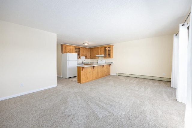 kitchen featuring sink, white fridge, light carpet, kitchen peninsula, and a baseboard radiator