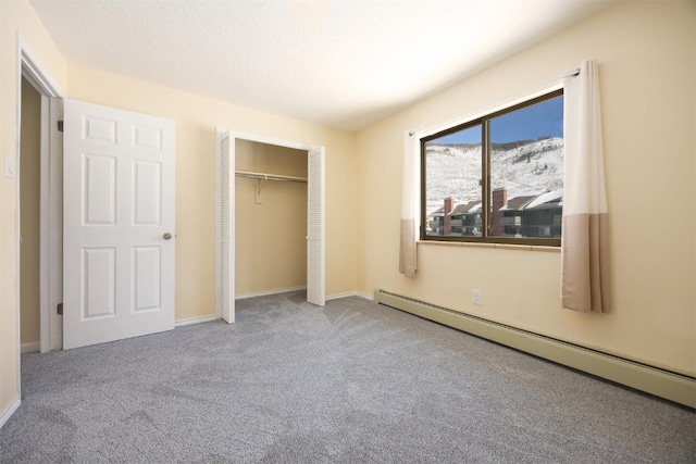 unfurnished bedroom with carpet floors, a closet, a baseboard radiator, and a mountain view