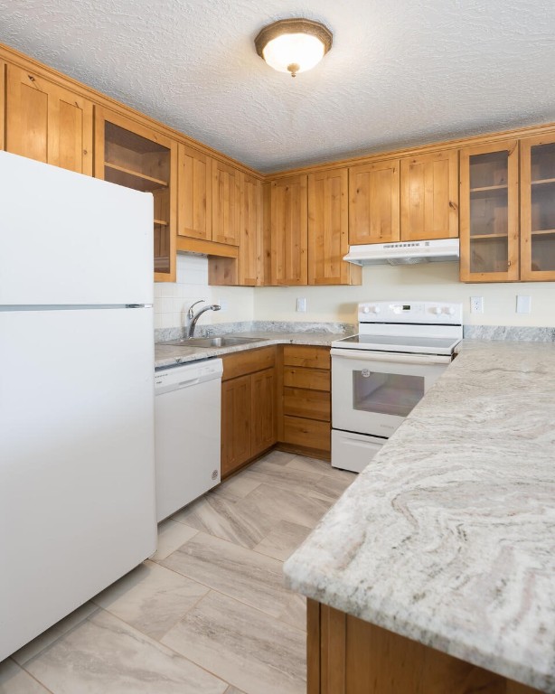 kitchen featuring white appliances, a textured ceiling, and sink