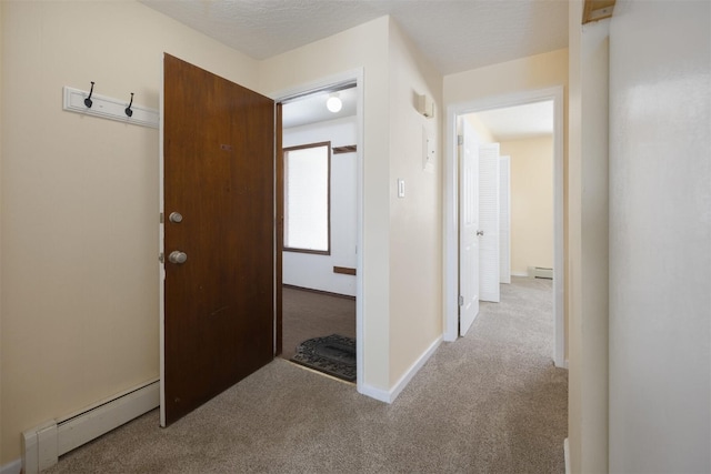 corridor featuring a baseboard heating unit, a textured ceiling, and light colored carpet