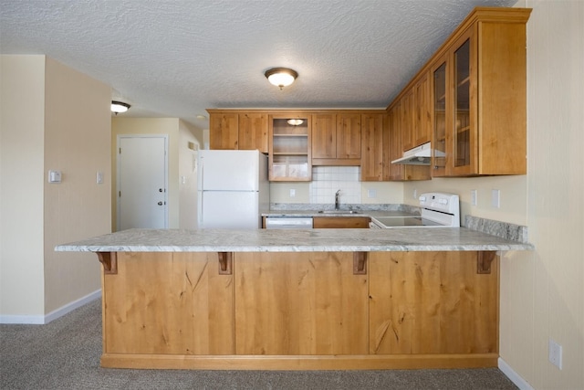 kitchen featuring white appliances, kitchen peninsula, carpet floors, and sink