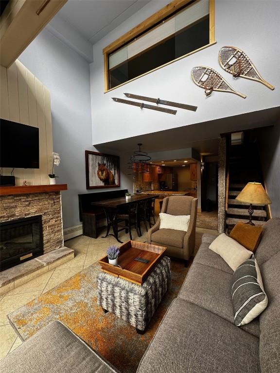 tiled living room with a stone fireplace and a baseboard radiator