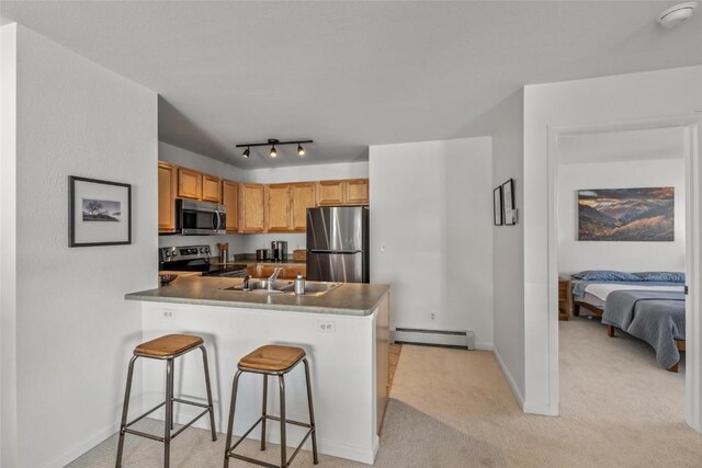 kitchen with appliances with stainless steel finishes, a baseboard radiator, sink, a kitchen breakfast bar, and kitchen peninsula