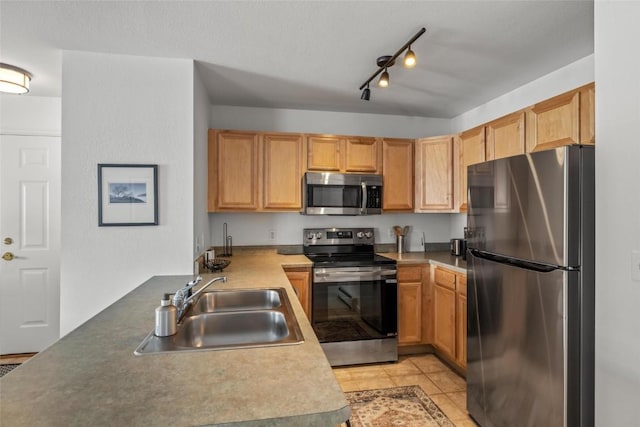 kitchen with appliances with stainless steel finishes, rail lighting, sink, and light tile patterned floors