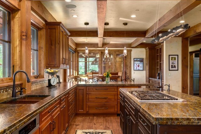 kitchen featuring light wood-type flooring, sink, pendant lighting, beam ceiling, and stainless steel gas stovetop