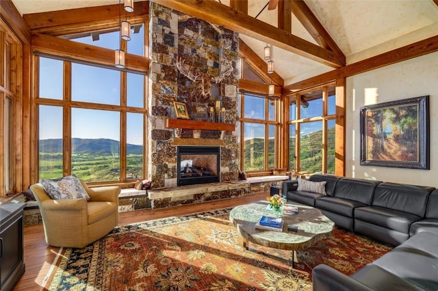 living room with beam ceiling, a stone fireplace, high vaulted ceiling, a mountain view, and wood-type flooring