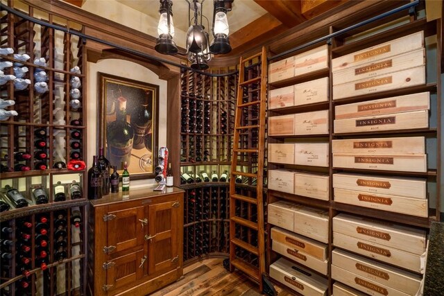 wine area featuring hardwood / wood-style flooring and an inviting chandelier