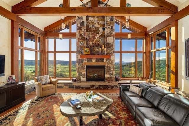 living room featuring a stone fireplace, plenty of natural light, and lofted ceiling with beams