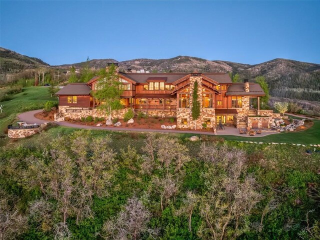 rear view of property featuring a lawn, a mountain view, and a patio