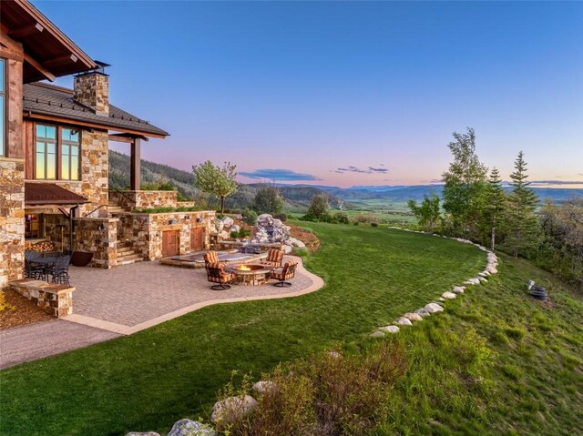 yard at dusk featuring a fire pit and a patio area