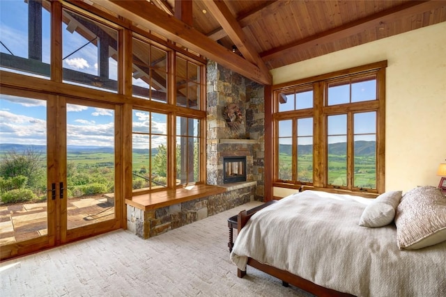 bedroom with access to exterior, wooden ceiling, a stone fireplace, high vaulted ceiling, and beamed ceiling