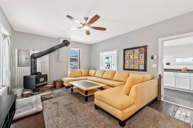 living room with a wood stove, ceiling fan, and dark hardwood / wood-style floors