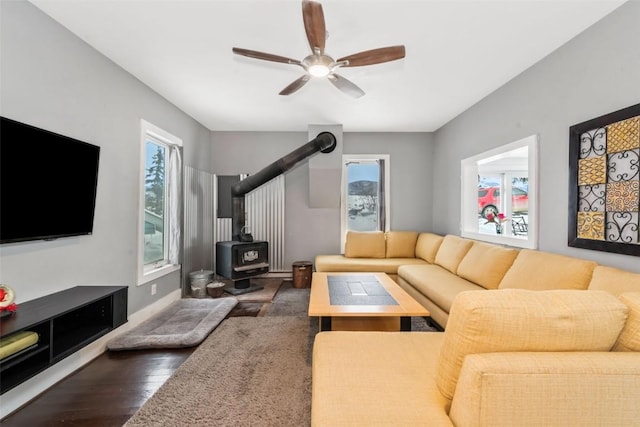 living room featuring a wood stove, dark hardwood / wood-style flooring, and ceiling fan