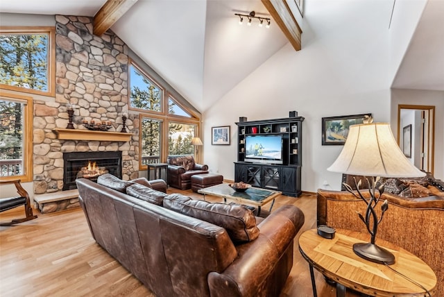 living room featuring beam ceiling, a stone fireplace, light hardwood / wood-style flooring, and high vaulted ceiling