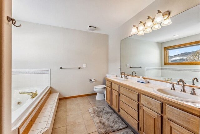 bathroom featuring tile patterned floors, tiled tub, vanity, and toilet