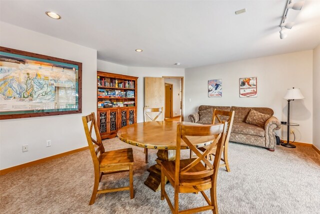 carpeted dining room with rail lighting