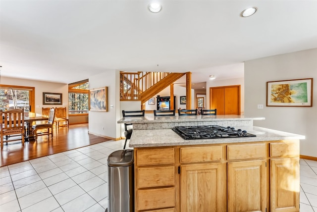 kitchen with black gas stovetop, a kitchen island, and light tile patterned flooring