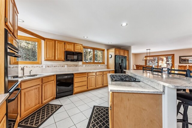 kitchen featuring sink, tasteful backsplash, hanging light fixtures, and black appliances